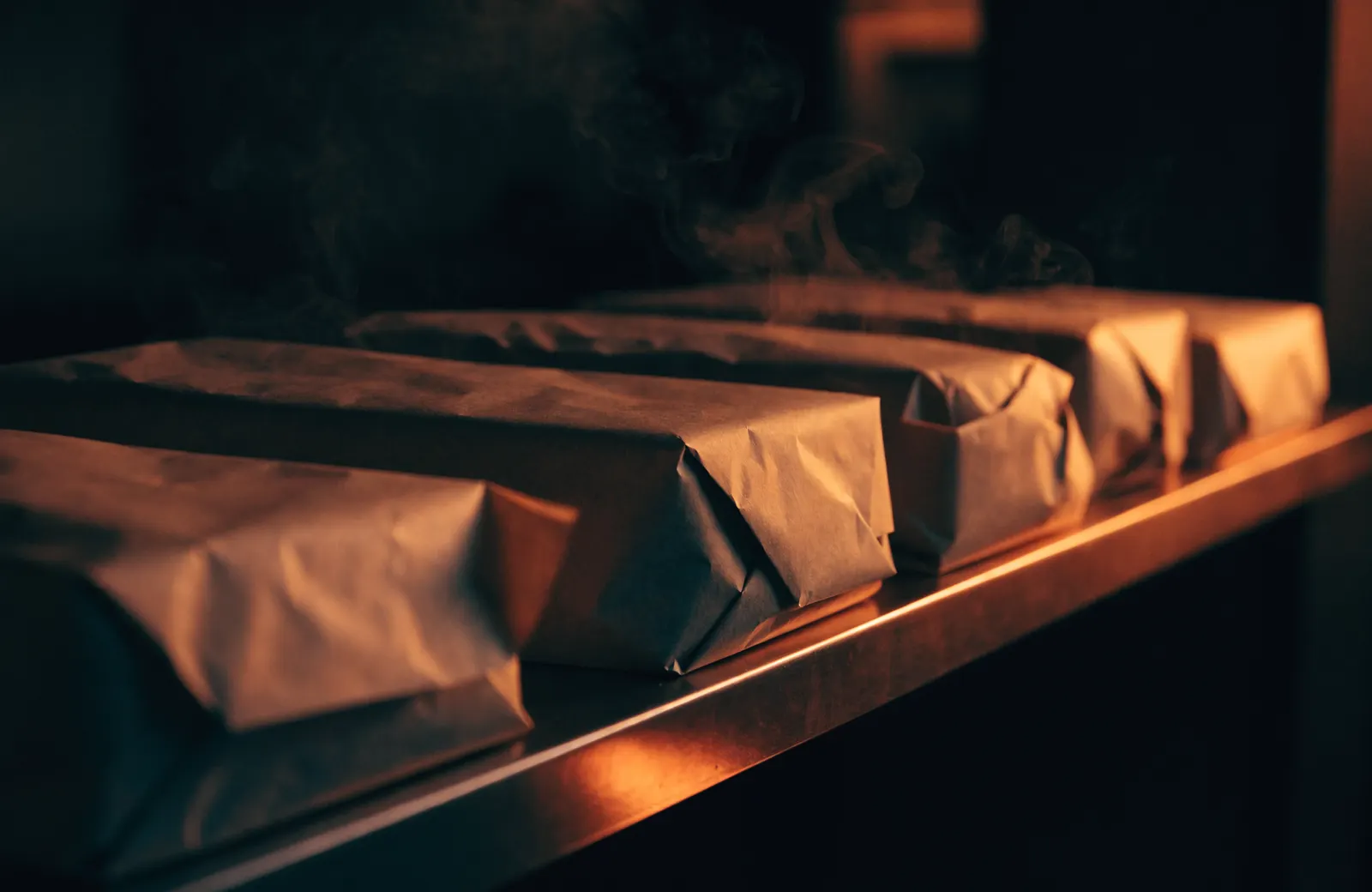 Wrapped takeout orders waiting on a pickup shelf in warm light